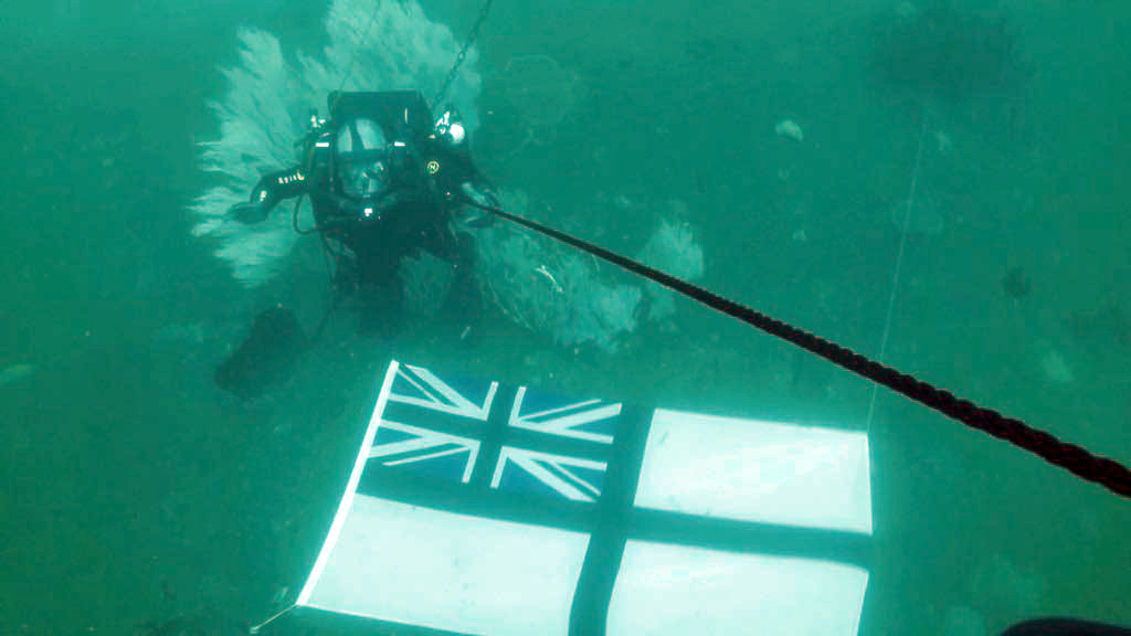 RN Diver 'flies' the RN standard on HMS Hermes